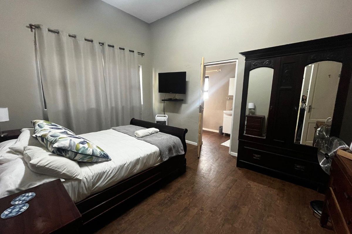 Spacious bedroom featuring dark wood-look flooring, high ceilings, and an en-suite bathroom access.