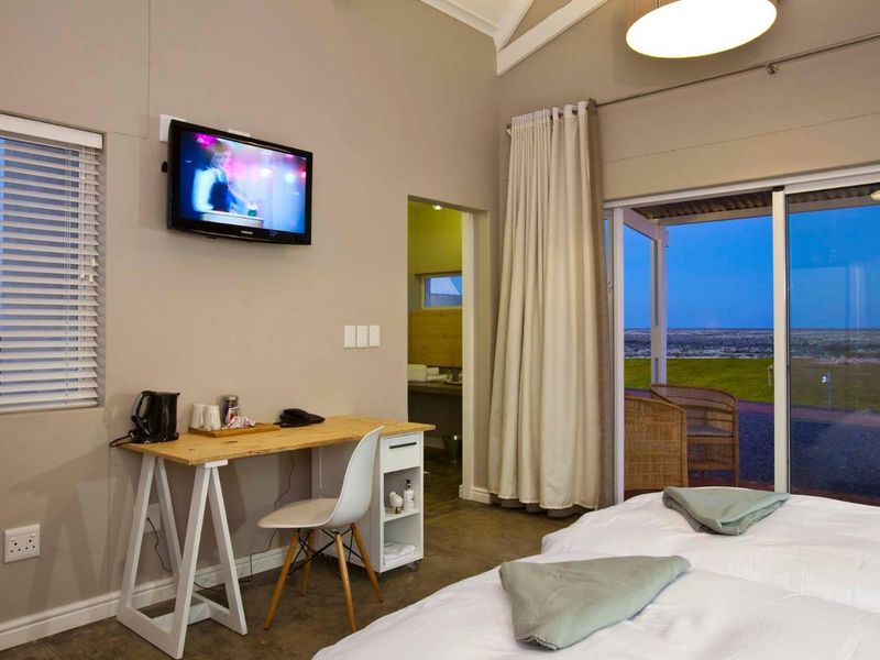 A well-maintained bedroom featuring vaulted ceilings, tiled floors, and large sliding glass doors that open to a scenic outdoor view.