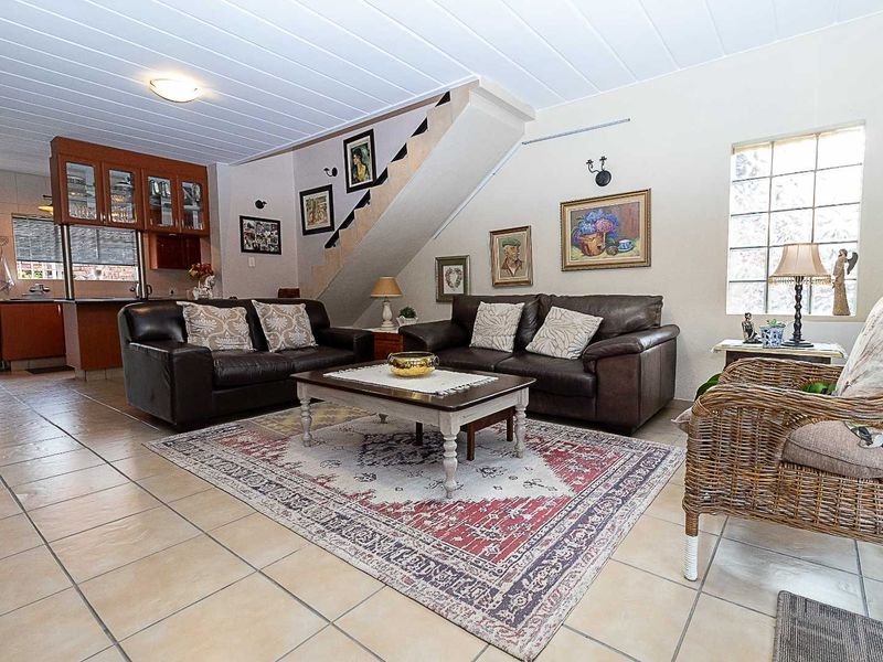 Open plan living area featuring ceramic tile flooring, a staircase, and an integrated kitchen with wooden cabinetry.