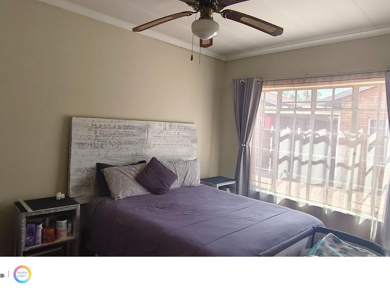 A standard bedroom featuring a ceiling fan and a large window with curtain rails, providing natural light.