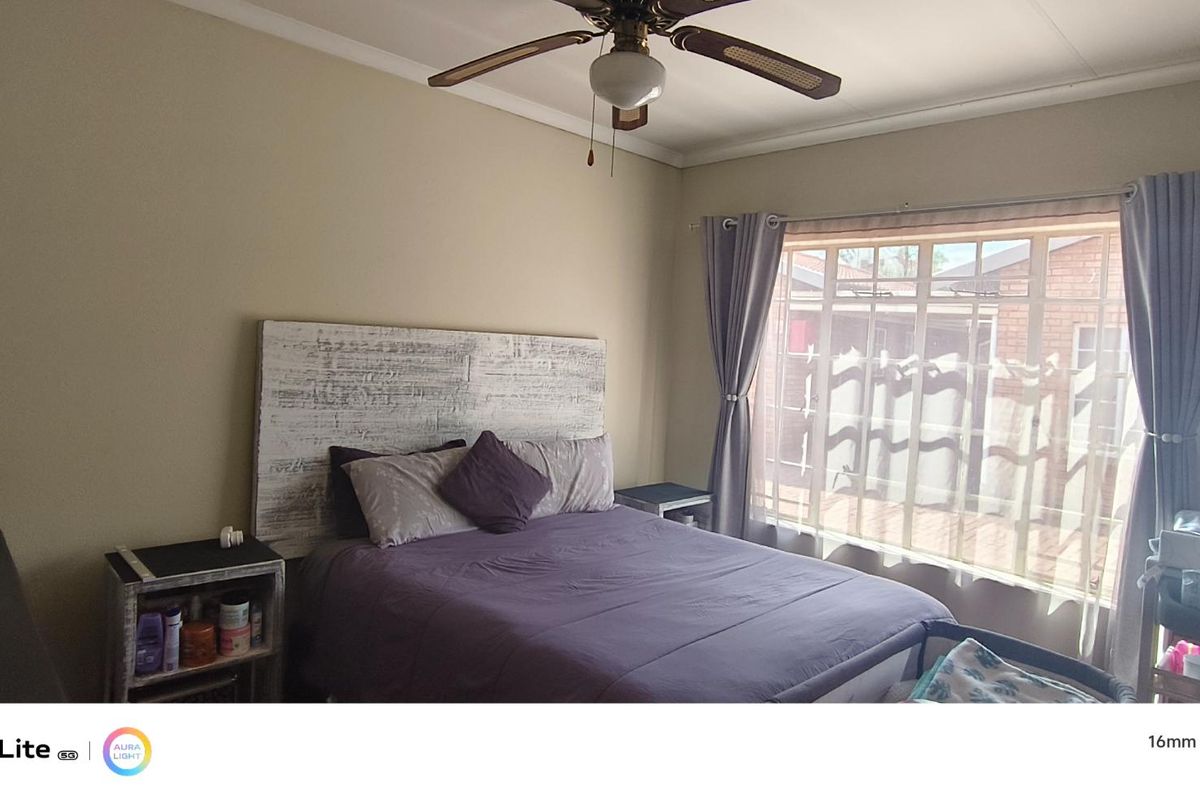 A standard bedroom featuring a ceiling fan and a large window with curtain rails, providing natural light.