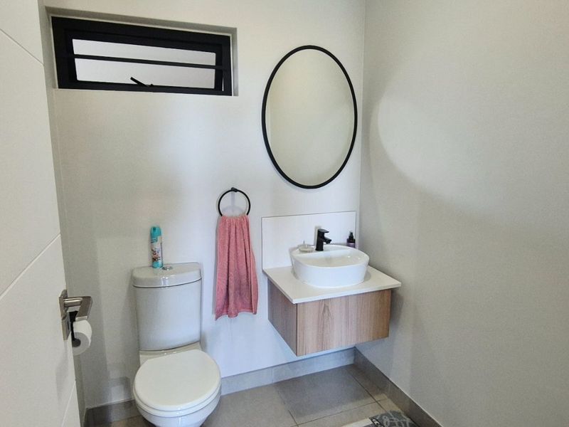 A modern guest bathroom featuring a wall-mounted vanity with a vessel sink, a sleek black-framed mirror, and a clean, minimalist design.