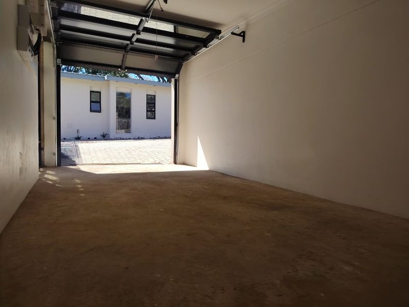 A spacious, empty garage featuring a modern sectional door and concrete flooring, providing secure parking or additional storage space.