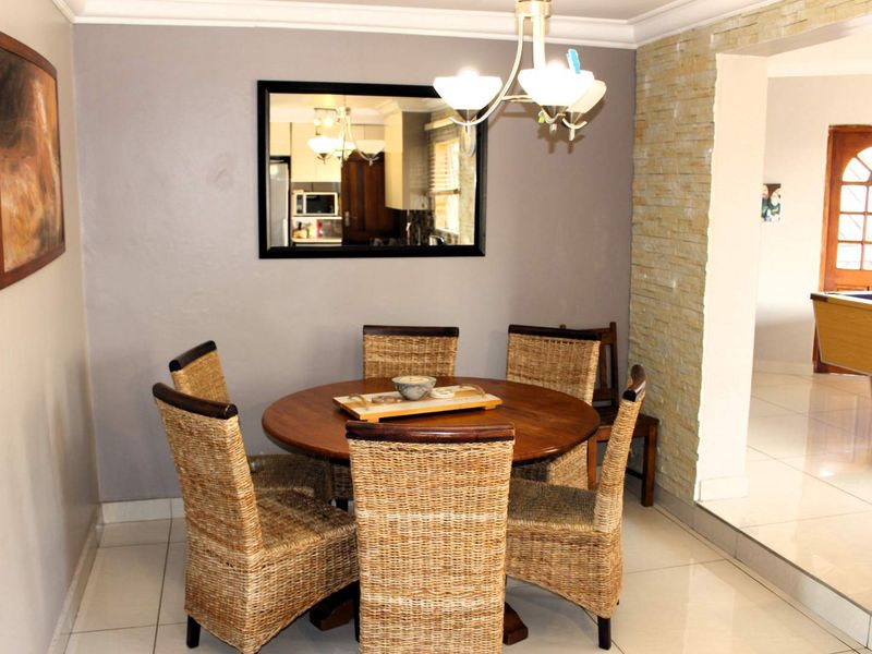 A dining area featuring tiled flooring, a stone accent wall, and a classic chandelier, providing a warm and inviting space for meals.