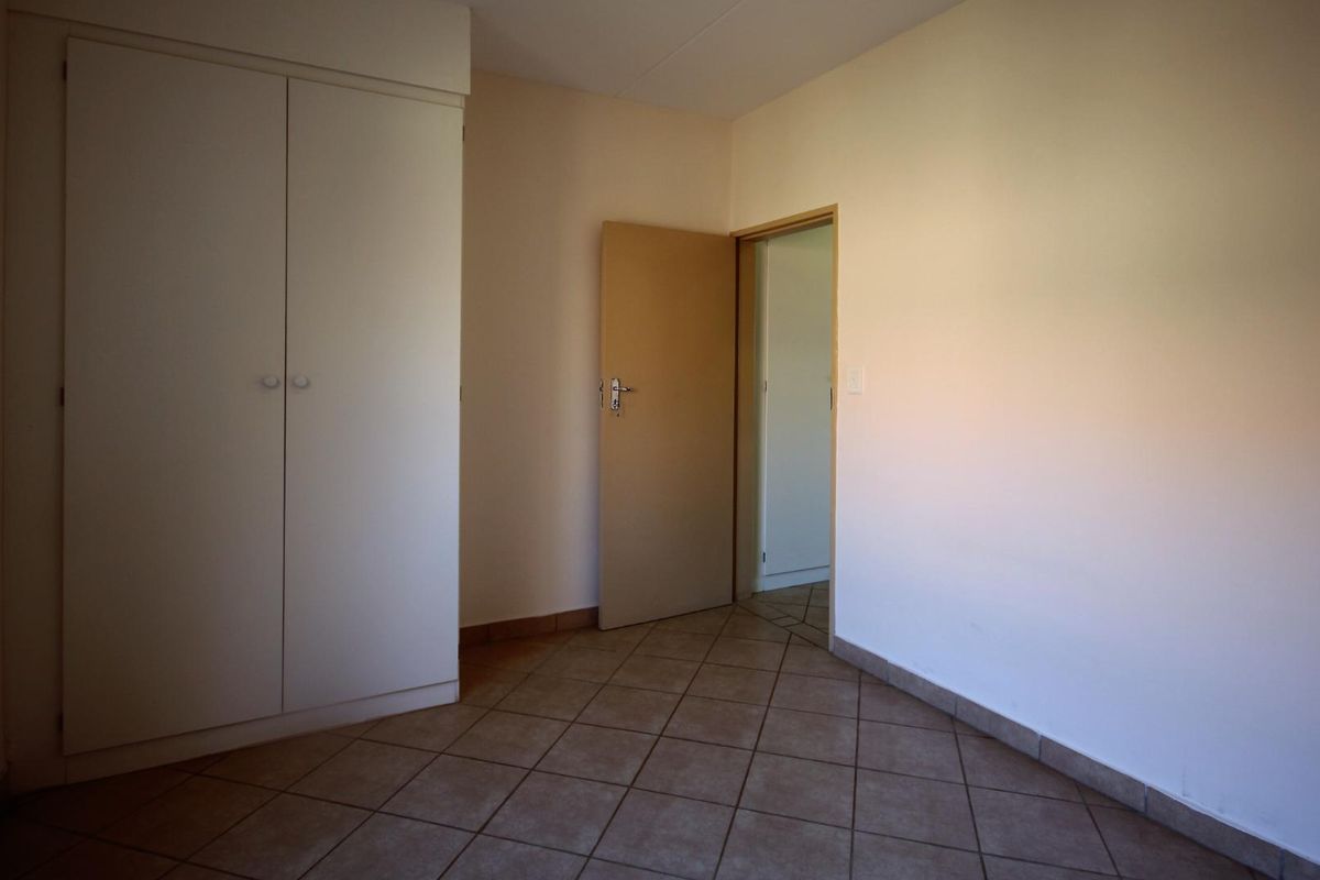 An empty bedroom featuring tiled flooring and a built-in wardrobe, offering a clean and neutral space ready for personalization.