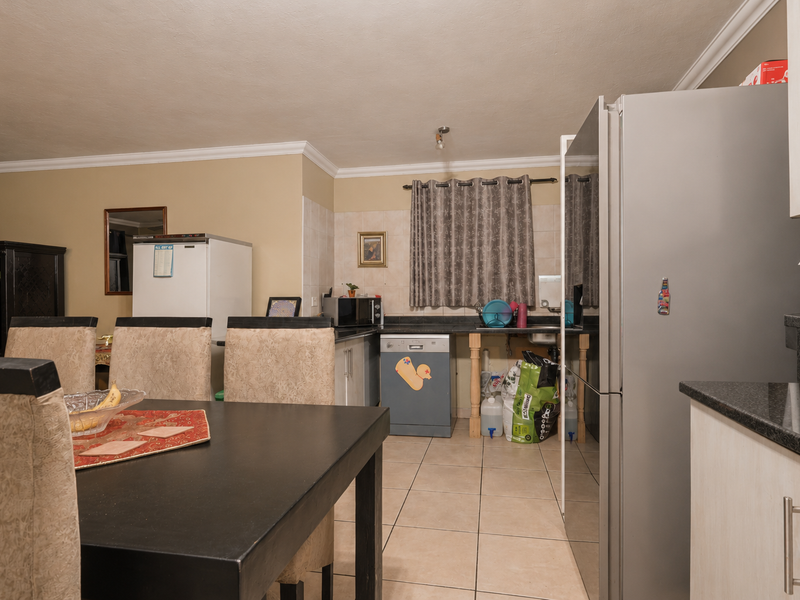 Open-plan kitchen and dining area featuring tiled flooring, granite countertops, and built-in cabinetry, offering a functional layout for daily living.