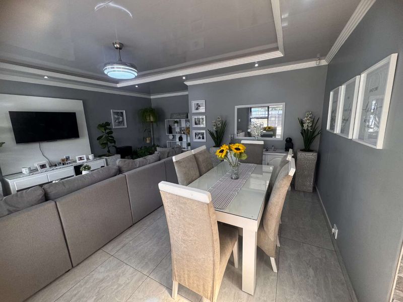 Spacious open-plan living and dining area featuring modern tiled flooring, recessed ceiling lighting, and a sleek built-in media wall.