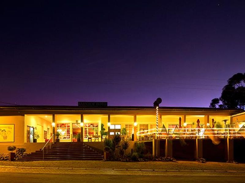Night view of the hotel exterior featuring a wide covered veranda, concrete entrance stairs, and illuminated facade.
