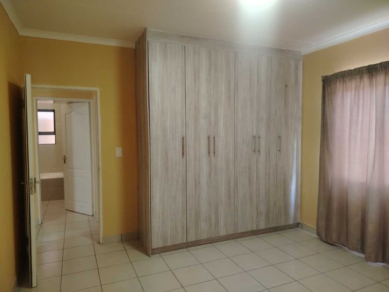 A bedroom featuring built-in cupboards, tiled flooring, and direct access to an adjoining bathroom.