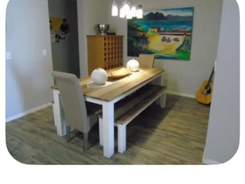 A dining room area featuring laminate flooring and a central pendant light fixture.