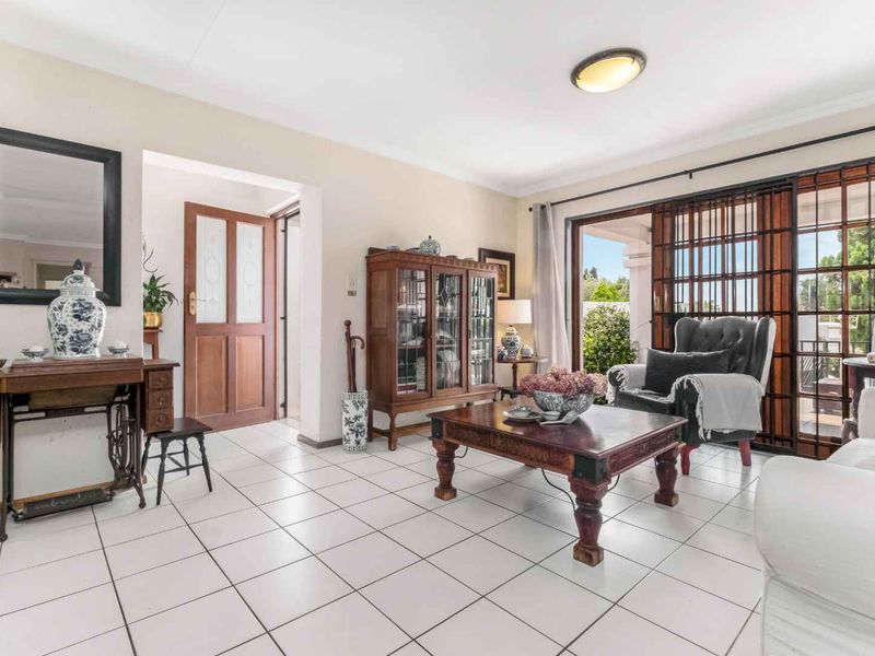 A bright living room featuring white tiled flooring and large sliding glass doors that provide access to the outdoor area.