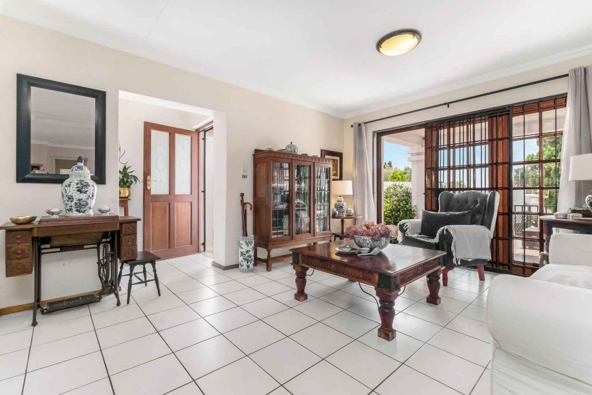 A bright living room featuring white tiled flooring and large sliding glass doors that provide access to the outdoor area.