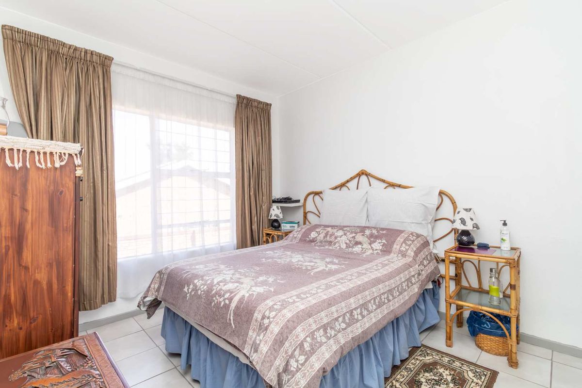 A functional bedroom featuring tiled flooring and a large window with curtain tracks.
