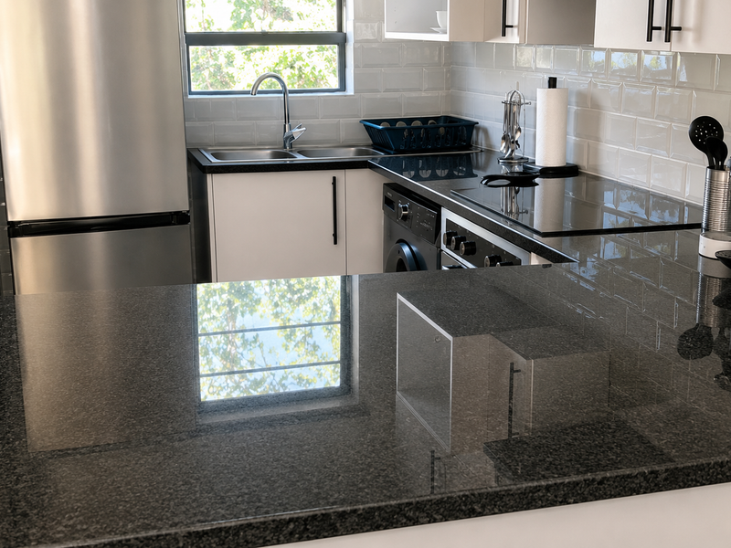 Modern kitchen featuring dark granite countertops, white subway tile backsplash, and integrated stainless steel appliances in a clean, functional layout.
