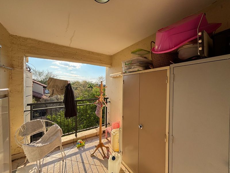 A covered balcony featuring tiled flooring, a metal balustrade, and built-in storage cabinets, offering an outdoor space with potential for improvement.