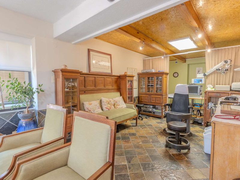 A multi-purpose utility space featuring slate tile flooring, exposed timber ceiling beams, and a skylight, currently utilized as a professional or clinical workspace.