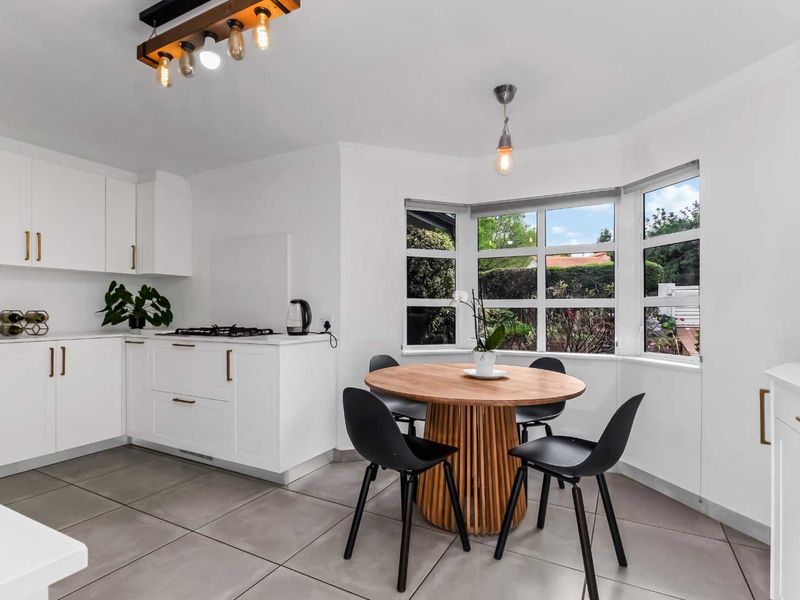 A bright, modern kitchen featuring white cabinetry, a gas cooktop, tiled flooring, and a charming bay window area suitable for a breakfast nook.