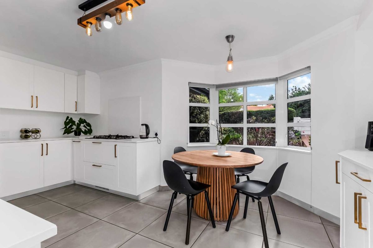 A bright, modern kitchen featuring white cabinetry, a gas cooktop, tiled flooring, and a charming bay window area suitable for a breakfast nook.
