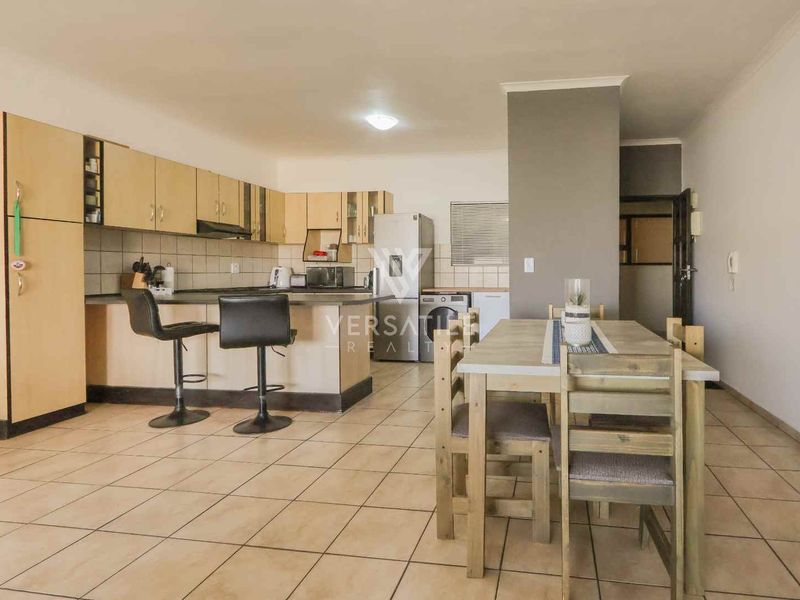 Open-plan kitchen and dining area featuring tiled flooring, built-in cabinetry, and a breakfast counter, providing a functional living space.