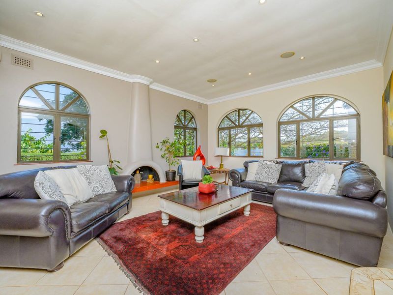 Spacious living room featuring arched windows, a unique built-in fireplace, recessed lighting, and neutral tiled flooring.