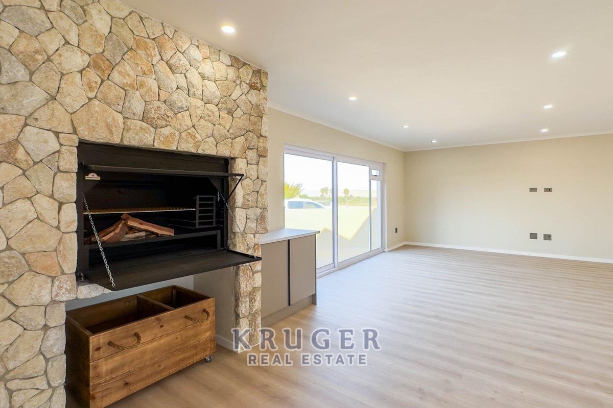 Spacious living area featuring a prominent stone-clad built-in fireplace, modern laminate flooring, and large sliding glass doors providing ample natural light.