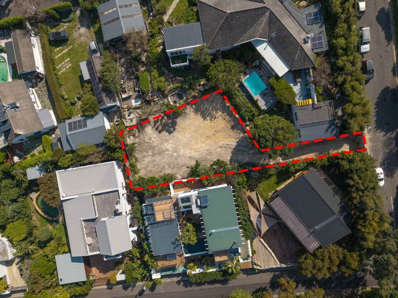 Aerial view of a vacant residential plot situated within an established neighborhood, featuring clear boundaries and access from the street.