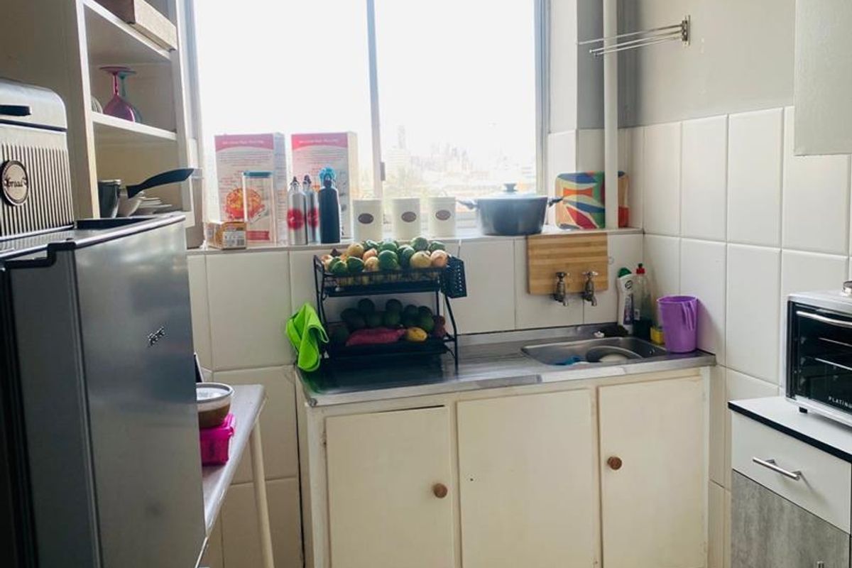 A compact kitchen featuring a stainless steel sink, tiled splashback, and built-in cabinetry, offering a functional layout with potential for cosmetic updates.