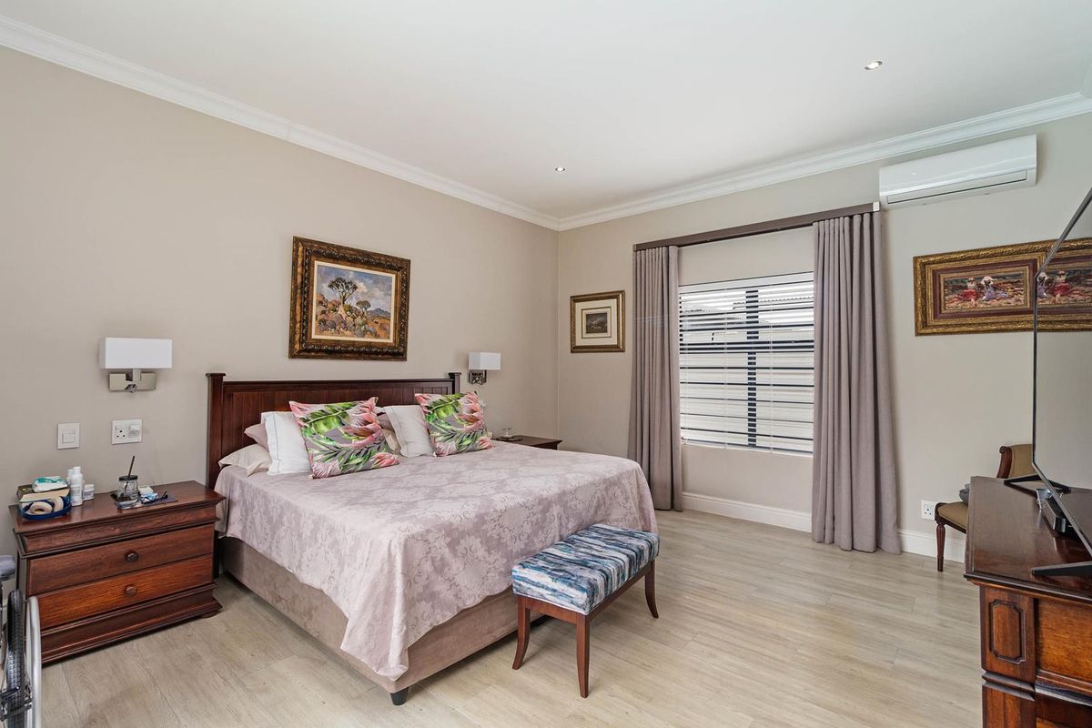 Spacious bedroom featuring light wood-look flooring, recessed ceiling lighting, and a wall-mounted air conditioning unit.
