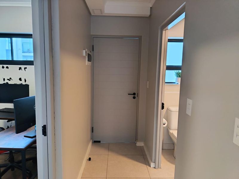 A clean and neutral hallway connecting multiple rooms, featuring tiled flooring and modern internal doors.