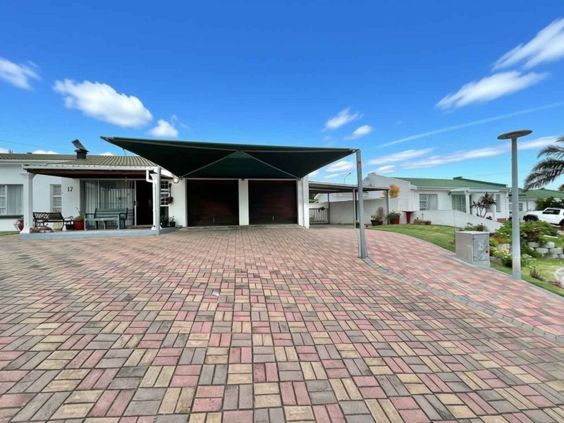 Front exterior view of the property featuring a paved driveway, double garage with a shade sail carport, and secure entrance.
