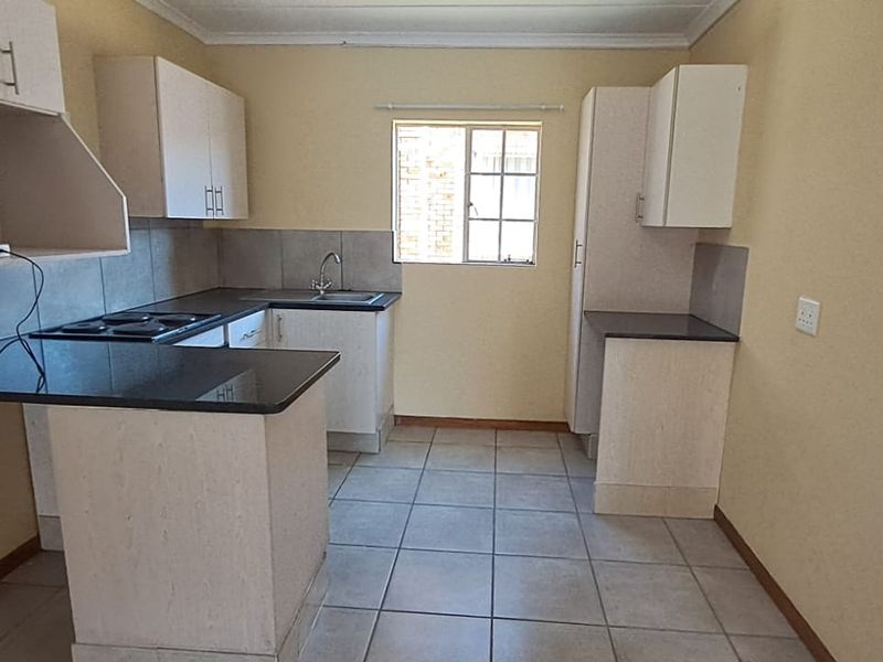 A functional kitchen featuring laminate cabinetry, granite countertops, an electric hob, and tiled flooring, offering a clean and practical workspace.