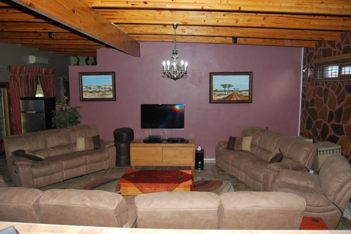 Spacious living room featuring exposed timber ceiling beams, tiled flooring, and a feature wall with stone cladding accents.