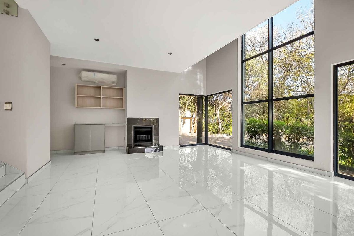 Spacious living area featuring large floor-to-ceiling windows, polished marble-look tile flooring, and a built-in fireplace with integrated cabinetry.