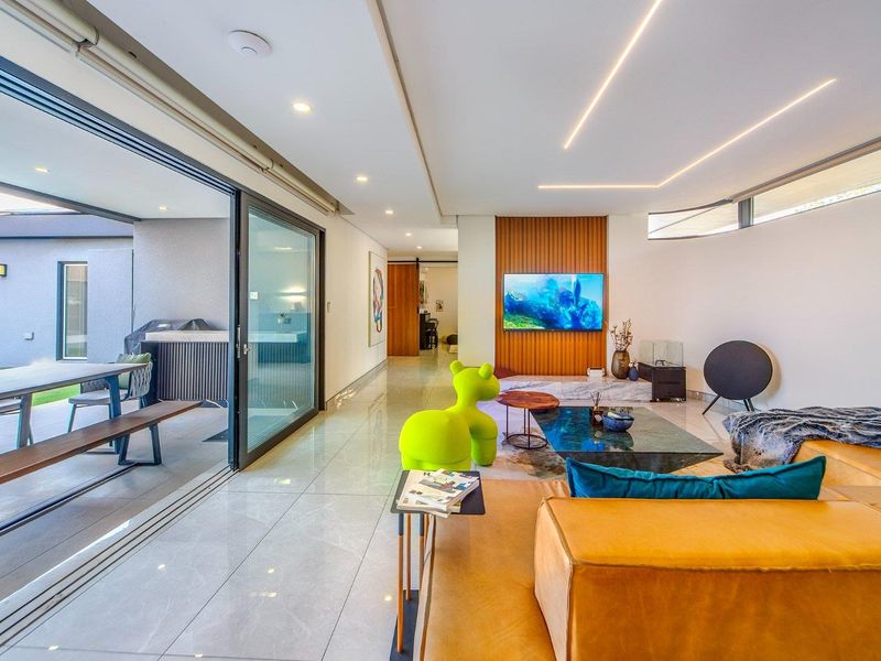 Modern open-plan living area featuring large format tiles, recessed lighting, and a timber slat feature wall, seamlessly connecting to an outdoor patio.