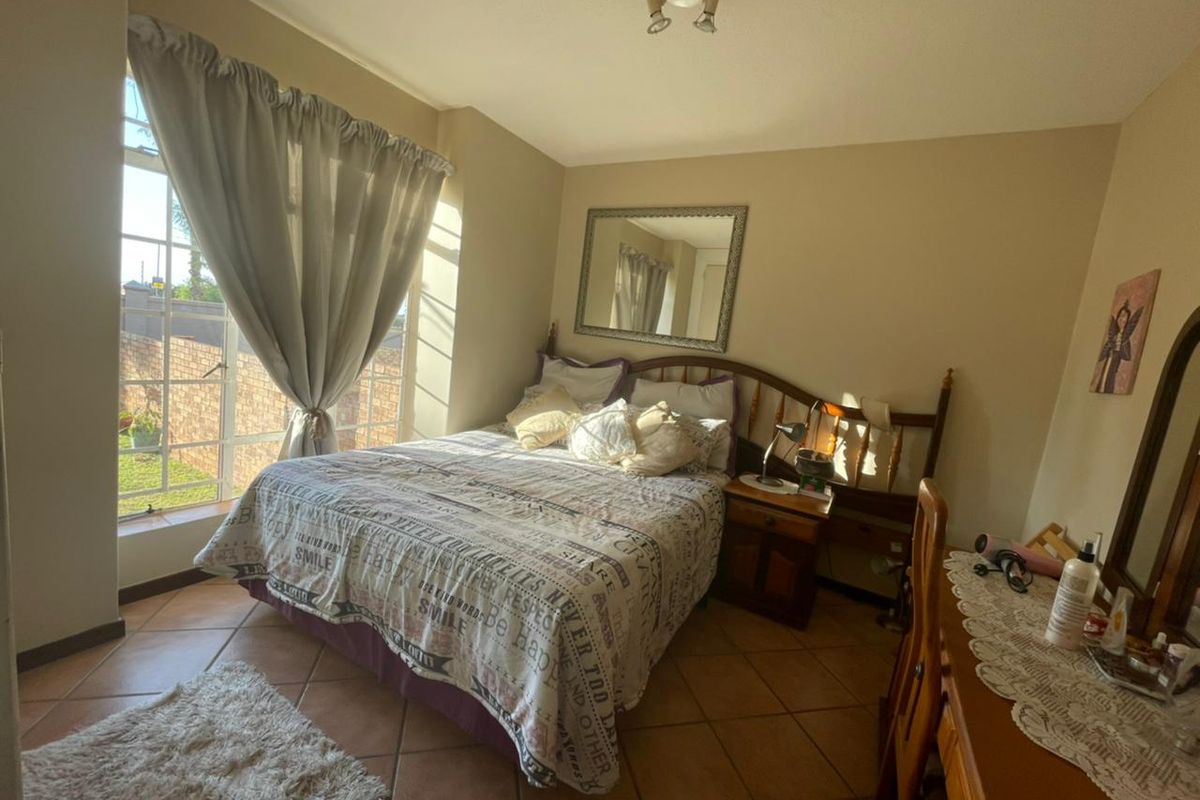 A bedroom featuring tiled flooring, a large window with natural light, and a ceiling-mounted light fixture.
