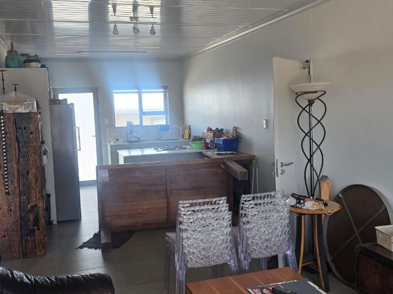 Open-plan living and kitchen area featuring tiled flooring and a central kitchen island, providing a functional and versatile space for daily living.