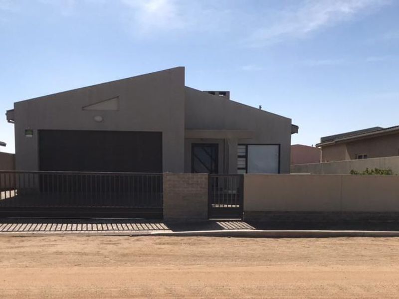 Front elevation of a modern single-story house featuring a single garage, secure perimeter walling, and gated access from the street.