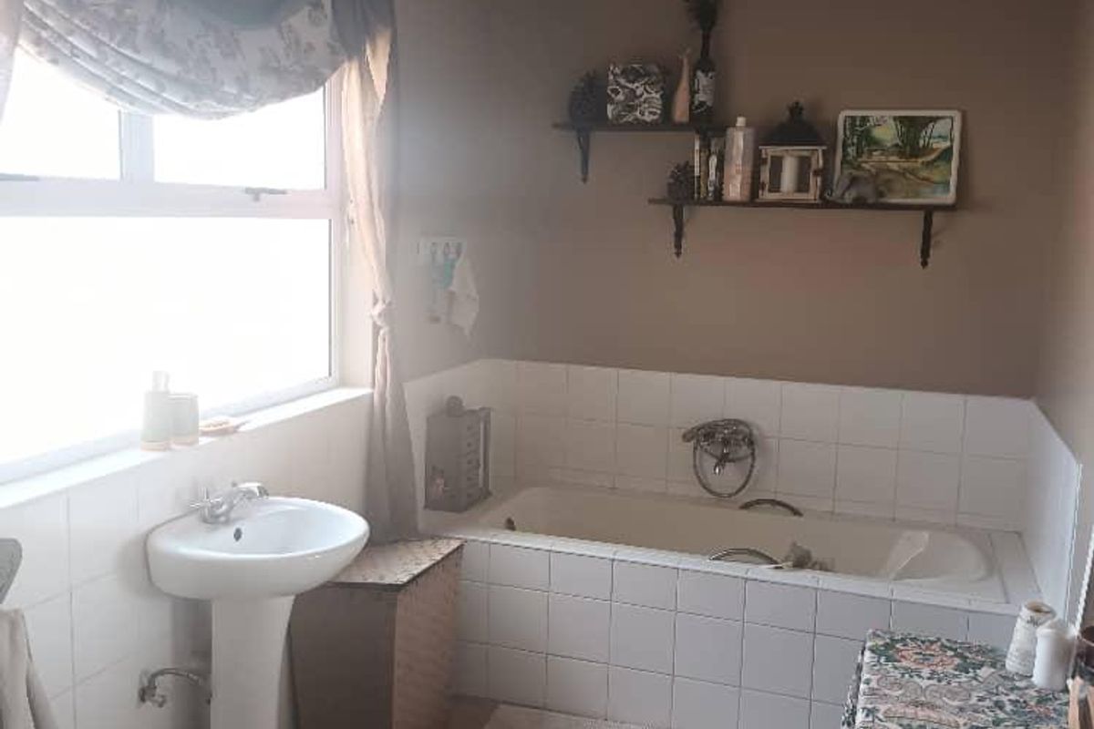 A functional bathroom featuring a pedestal basin and a tiled built-in bathtub with a neutral color palette.