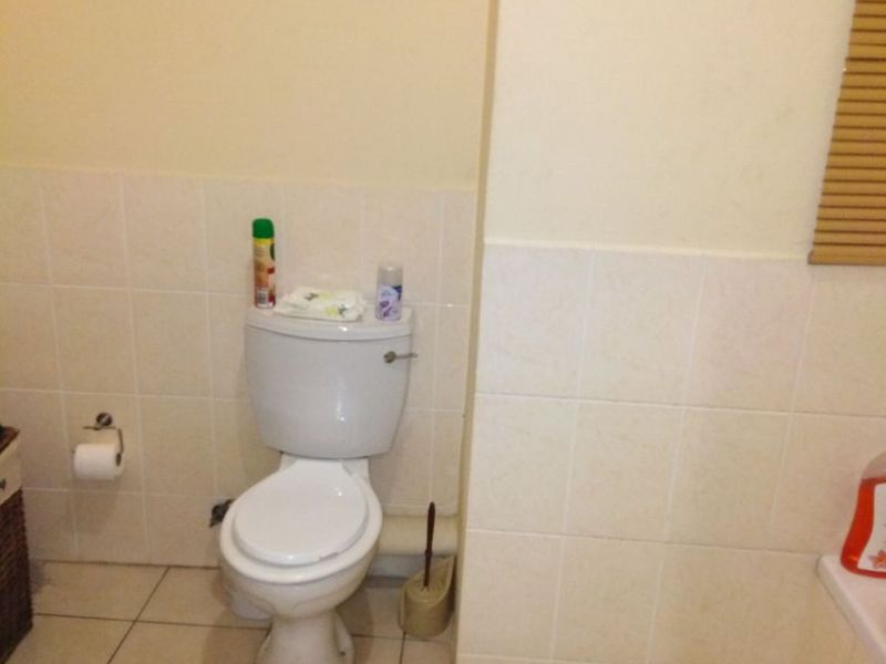 A functional bathroom featuring a standard toilet, tiled walls, and tiled flooring.