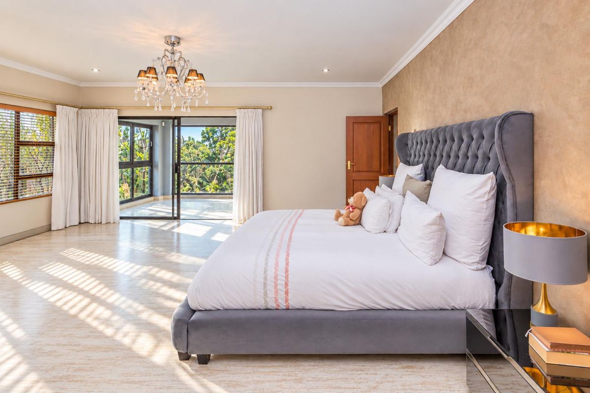 Spacious bedroom featuring tiled flooring, crown molding, a decorative chandelier, and large sliding glass doors opening to an outdoor balcony area.
