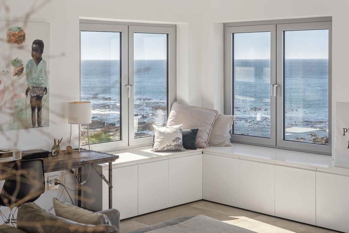 A bright living area featuring custom built-in cabinetry with a window seat, offering expansive ocean views through modern casement windows.