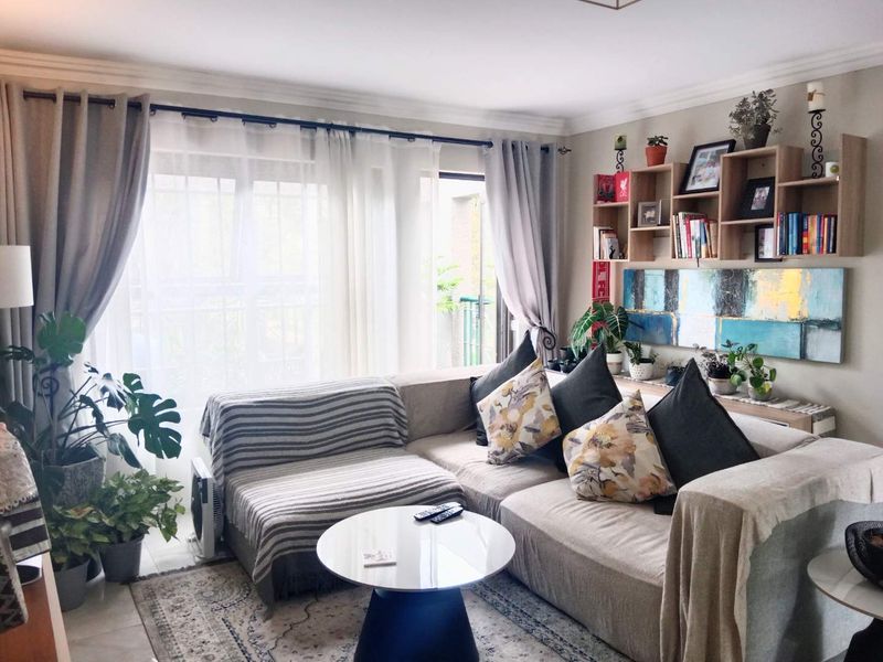 A cozy living room featuring crown molding, built-in wall shelving, and large sliding glass doors that provide ample natural light.