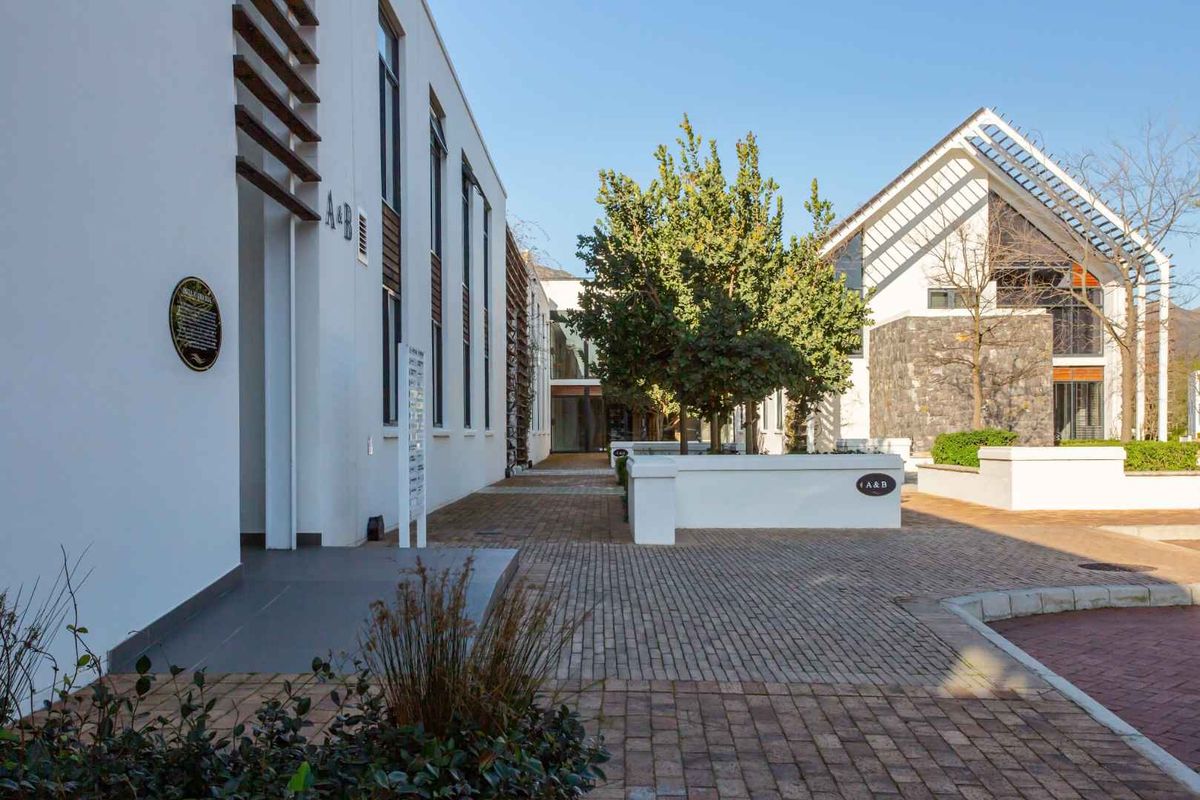 A well-maintained exterior courtyard area featuring paved walkways, modern architectural facades, and landscaped trees within a professional business complex.
