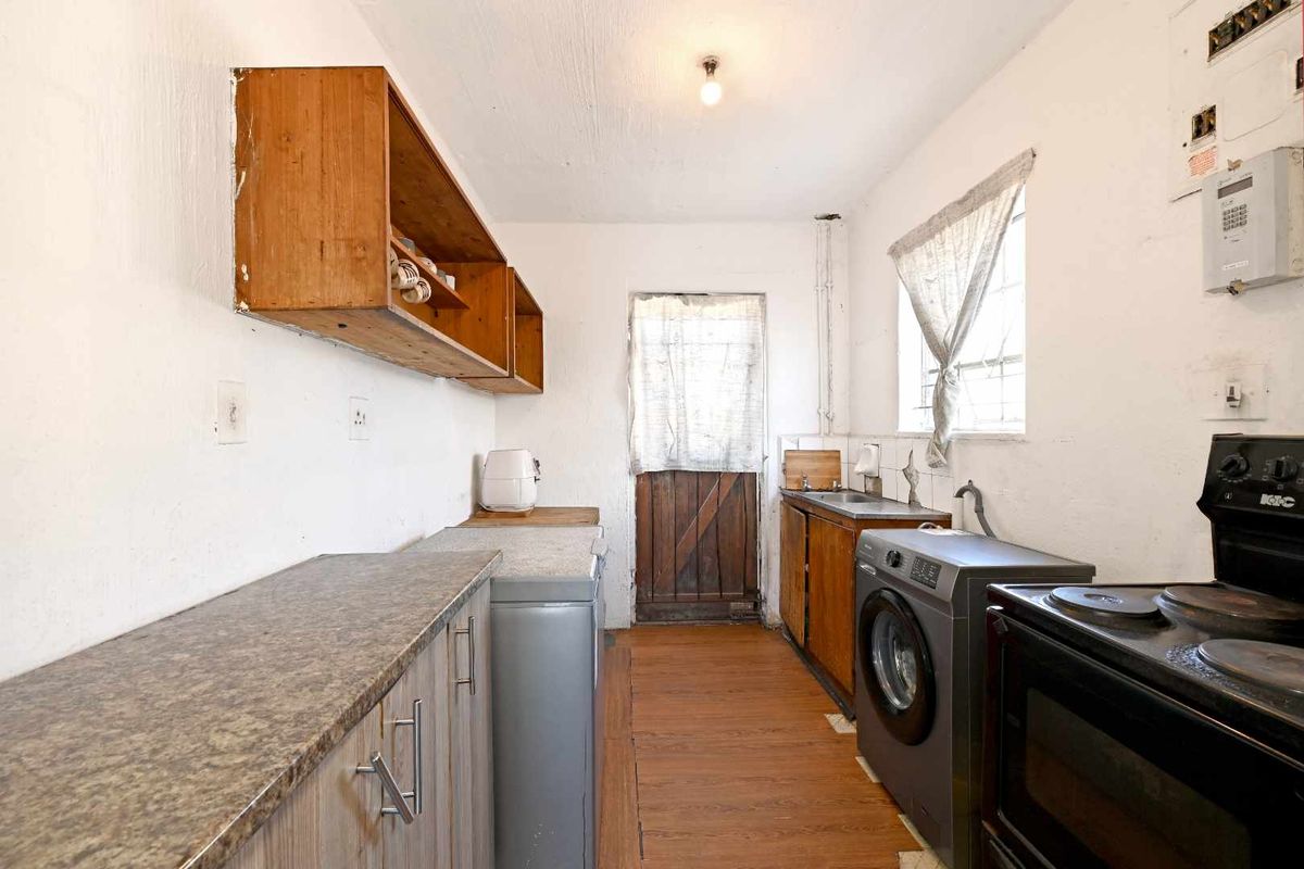 A functional laundry area featuring built-in cabinetry, laminate countertops, a stainless steel sink, and direct access to the exterior.