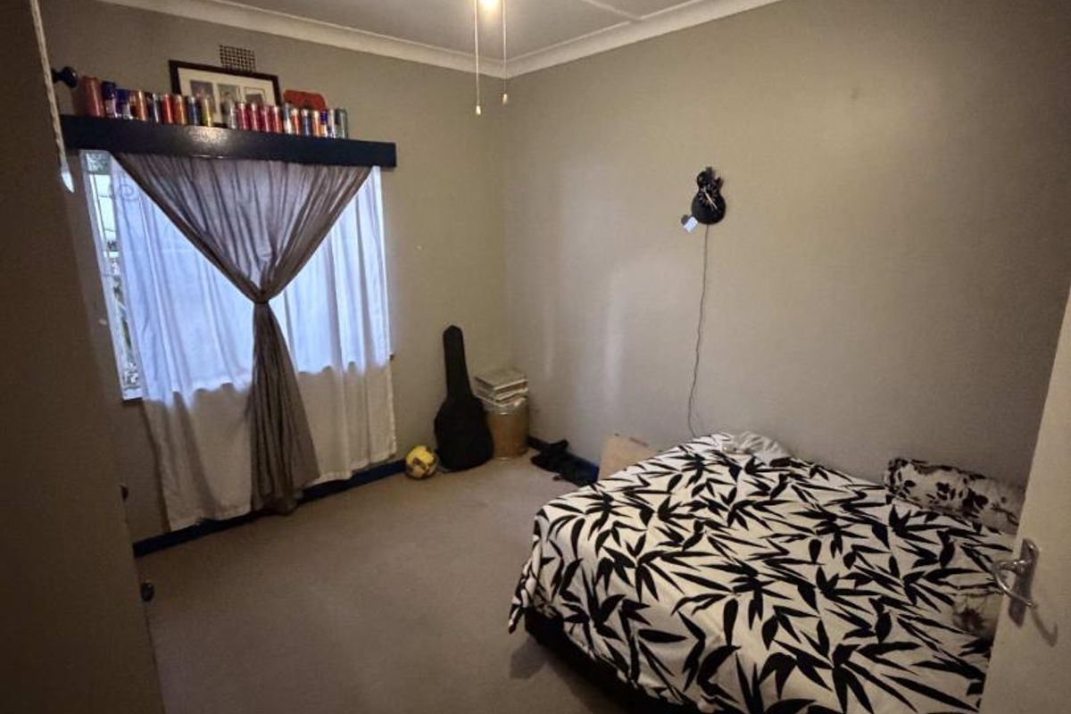 A standard bedroom featuring neutral wall tones, carpeted flooring, and a ceiling fan, providing a functional space for rest.