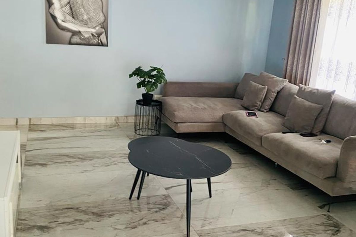 A bright living room featuring polished marble-look porcelain floor tiles, coved ceiling cornicing, and neutral wall finishes.