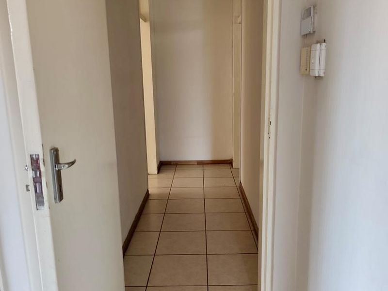 A functional interior hallway featuring neutral tiled flooring and standard door frames, providing access to multiple rooms within the cottage.