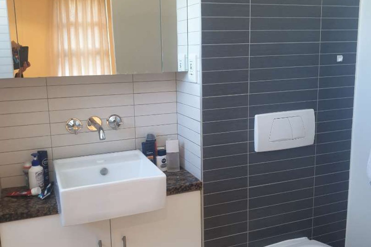 Modern bathroom featuring a wall-mounted toilet with concealed cistern, a vessel sink vanity, and contemporary tiled wall finishes.