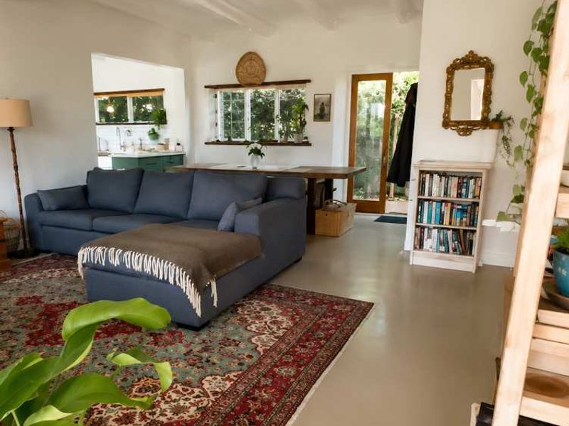 Bright open-plan living area featuring polished concrete floors, exposed beam ceilings, and a seamless flow to the kitchen and outdoor access.