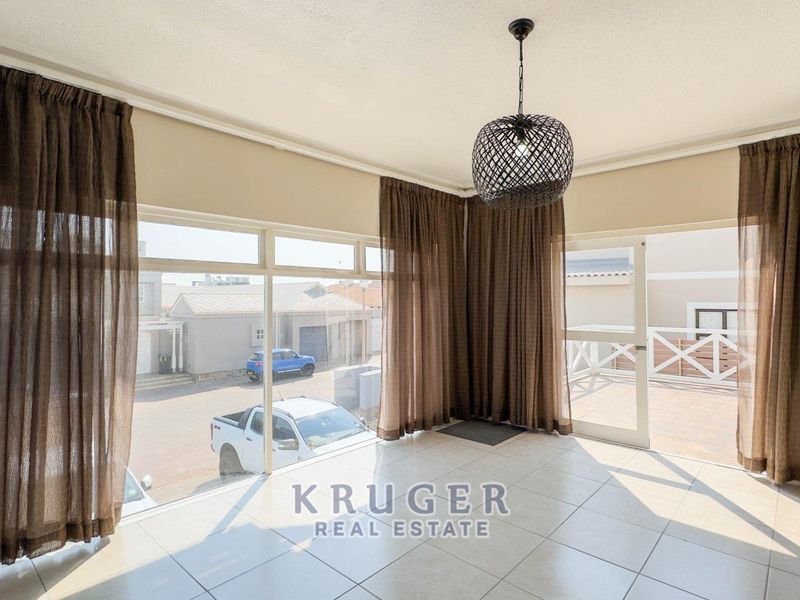 Bright and spacious living area featuring large windows, tiled flooring, and direct access to an outdoor patio space.